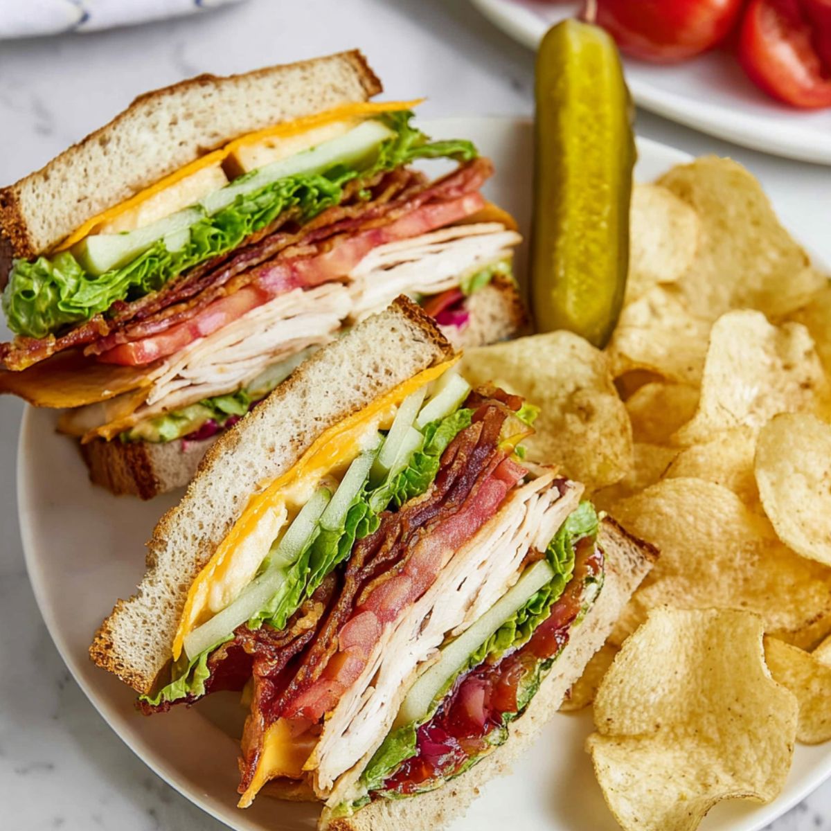 Chicken Club Sandwich cut into halves on a white plate, layered with lettuce, tomato, bacon, cheddar cheese, and sliced chicken breast, served with potato chips and a dill pickle, close-up, top-down view, vibrant and fresh lunch presentation.