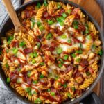 Monterey Chicken Skillet A fully cooked chicken pasta skillet with melted cheese, crispy bacon pieces, BBQ sauce, and sliced green onions, ready to serve.