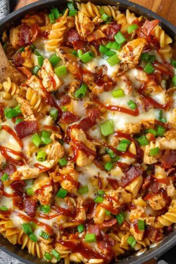 Easy Monterey Chicken Skillet Recipe 2 Monterey Chicken Skillet A fully cooked chicken pasta skillet with melted cheese, crispy bacon pieces, BBQ sauce, and sliced green onions, ready to serve.