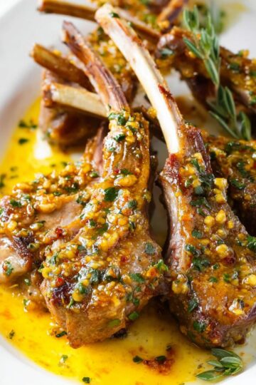 The Best Pan-Seared Lamb Chops Recipe 1 Pan-Seared Lamb Chops Close-up of cooked lamb chops on a white plate, topped with a golden garlic-herb sauce and garnished with fresh herbs, with a bright and clean presentation.