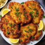 chicken schnitzel Golden, crispy chicken schnitzels plated and garnished with parsley and lemon wedges, ready to serve.