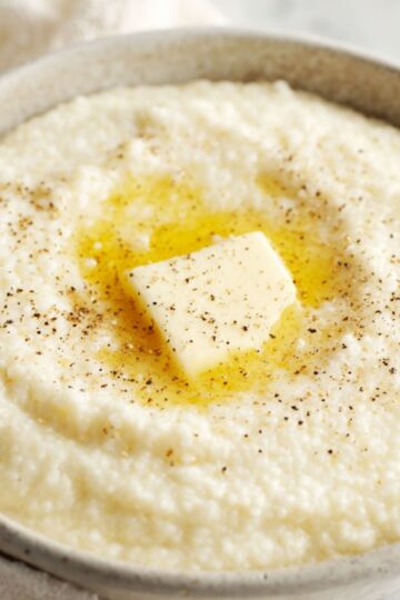 Delicious Creamy Grits Recipe 3 creamy grits A bowl of creamy grits served with a pat of melting butter on top, sprinkled with black pepper, highlighting a ready-to-eat breakfast presentation.