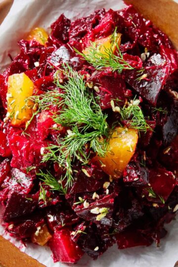 Delicious Grated Beet Salad Recipe 2 grated beet salad The finished beet salad placed on a plate lined with parchment paper, garnished with a sprig of dill. The salad looks vibrant and ready to serve.