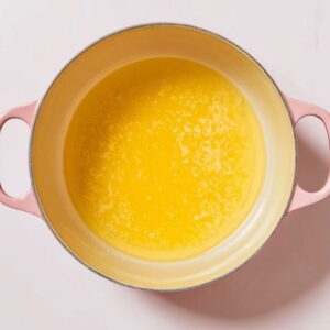 The Best Baked Peaches Recipe 14 A pink pot filled with a yellow liquid mixture, possibly melted butter or a sauce.