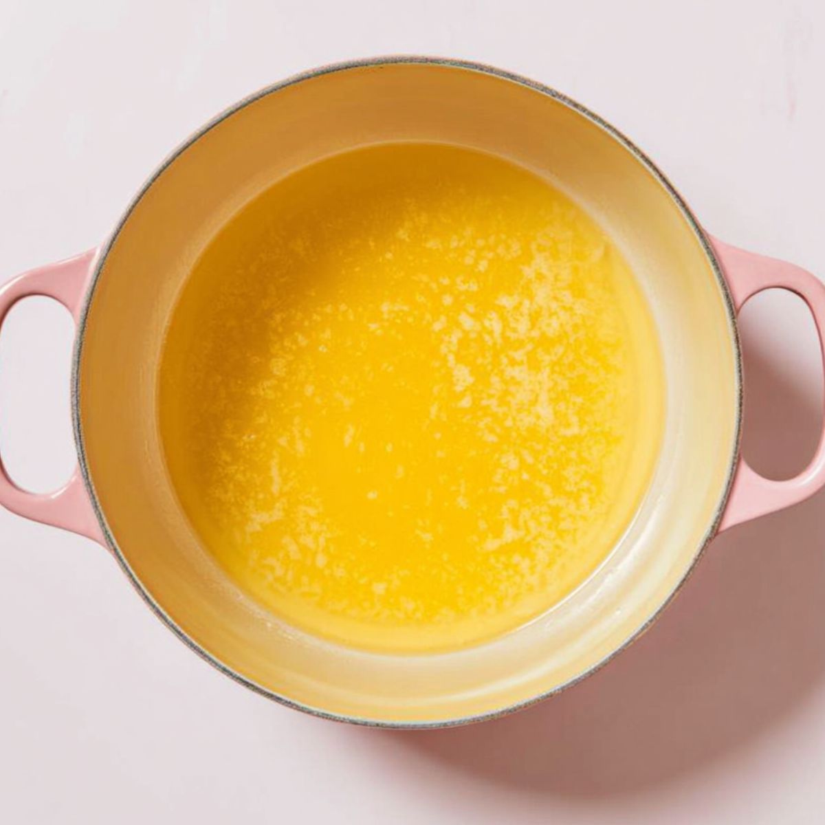 The Best Baked Peaches Recipe 10 A pink pot filled with a yellow liquid mixture, possibly melted butter or a sauce.