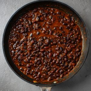 Best Black Bean Burritos Recipe 16 A savory pan of simmering black beans in a rich, flavorful sauce, creating a comforting and hearty dish with a deep, dark color and perfect texture.