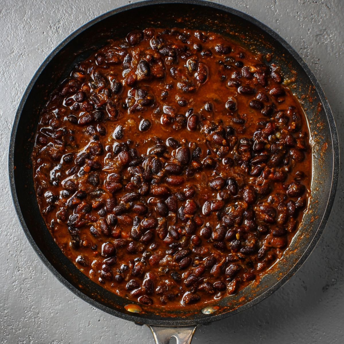 Best Black Bean Burritos Recipe 11 A savory pan of simmering black beans in a rich, flavorful sauce, creating a comforting and hearty dish with a deep, dark color and perfect texture.