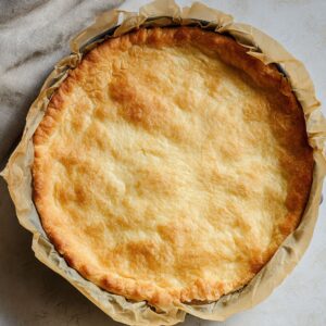 The Best Caramelized Onion Tart Recipe 16 Raw puff pastry sheet on parchment paper, with three whole red onions and small bowls of olive oil and balsamic vinegar nearby.