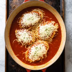 Easy Chicken Parmesan with Spaghetti Recipe 19 Cooked chicken parmesan on a baking sheet with melted mozzarella cheese over tomato sauce, ready for baking or serving.