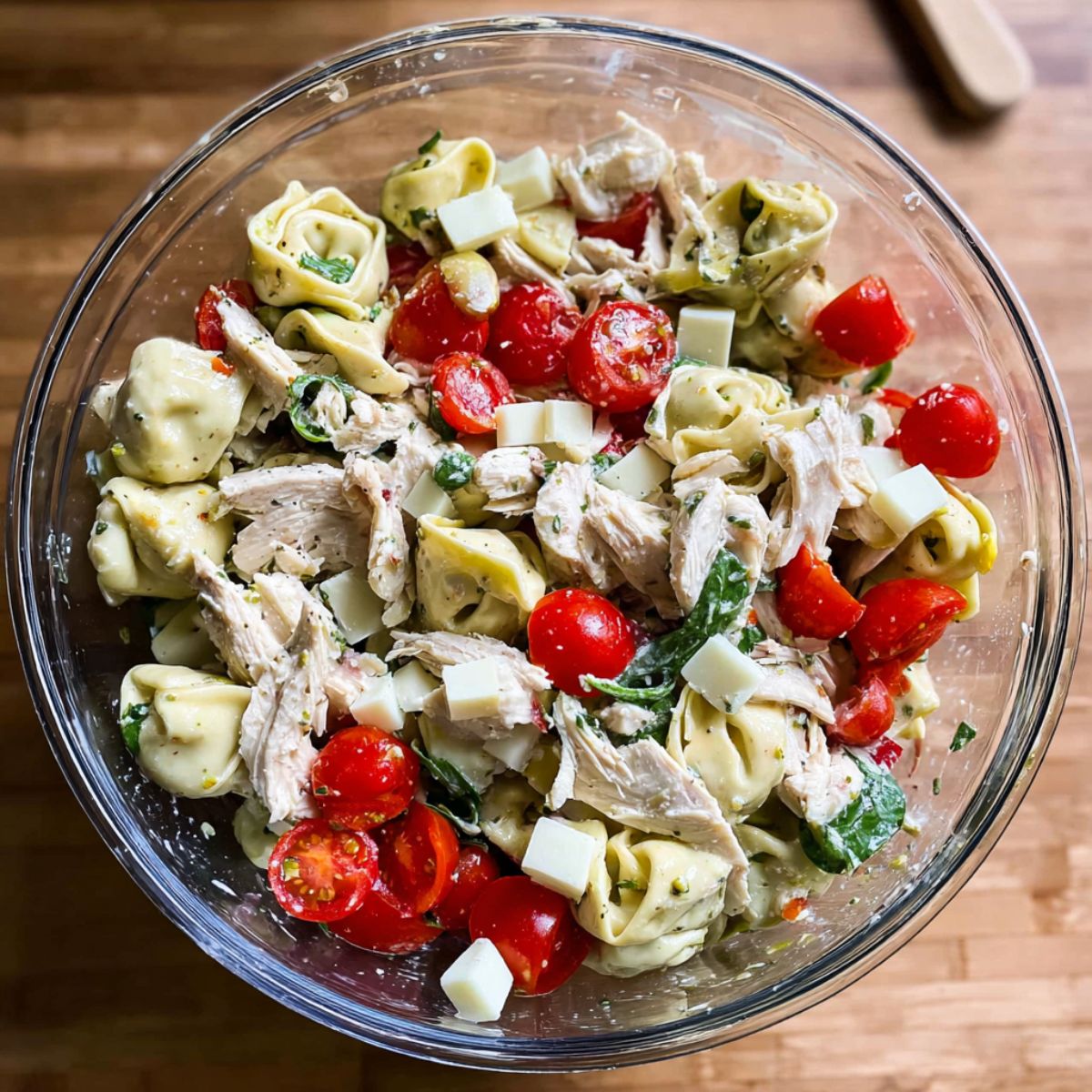 Best Chicken Tortellini Salad Recipe 10 Unmixed chicken tortellini pasta salad in a glass bowl with spinach tortellini, shredded chicken breast, cherry tomatoes, and cubed cheese