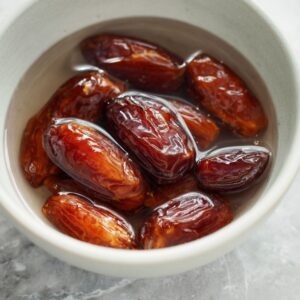 The Best Date Brownies Recipe 15 Medjool dates soaking in water in a white bowl before blending.