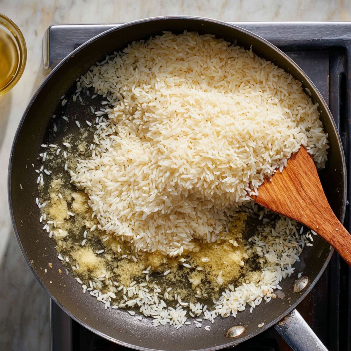 Healthy Garlic Butter Rice Recipe 11 The addition of the raw rice to the sautéed garlic and butter mixture in the pan.