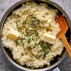 Healthy Garlic Butter Rice Recipe 18 Garlic butter rice in the pan, with butter and herbs sprinkled on top.