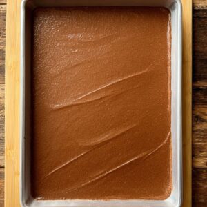 A rectangular baking pan evenly filled with smooth chocolate batter, ready for baking.