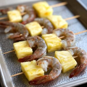Easy Grilled Pineapple Shrimp Skewers 15 Raw shrimp and pineapple skewers on a baking sheet, ready for cooking.