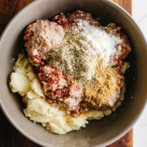 Best Homemade Kotleti Recipe 15 A mixing bowl containing ground meat combined with seasonings and other ingredients, ready to be shaped into meatballs.