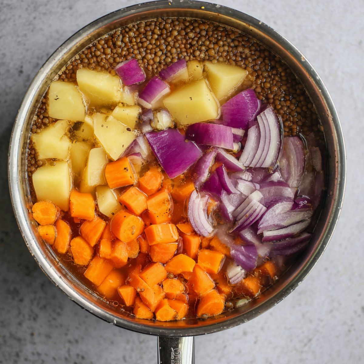 Delicious Lentil Patties Recipe 10 A saucepan filled with water, chopped carrots, potatoes, and red onion with lentils soaking or cooking inside.