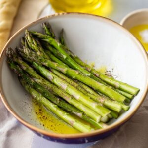 Easy Parmesan Asparagus Pastry Twists Recipe 14 A handful of fresh green asparagus spears in a bowl, showing their vibrant color and firm texture, before any preparation or cooking.