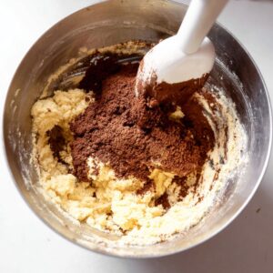 The Best Pinwheel Cookies Recipe 14 Mixing bowl with vanilla cookie dough and cocoa powder being incorporated to make the chocolate dough.