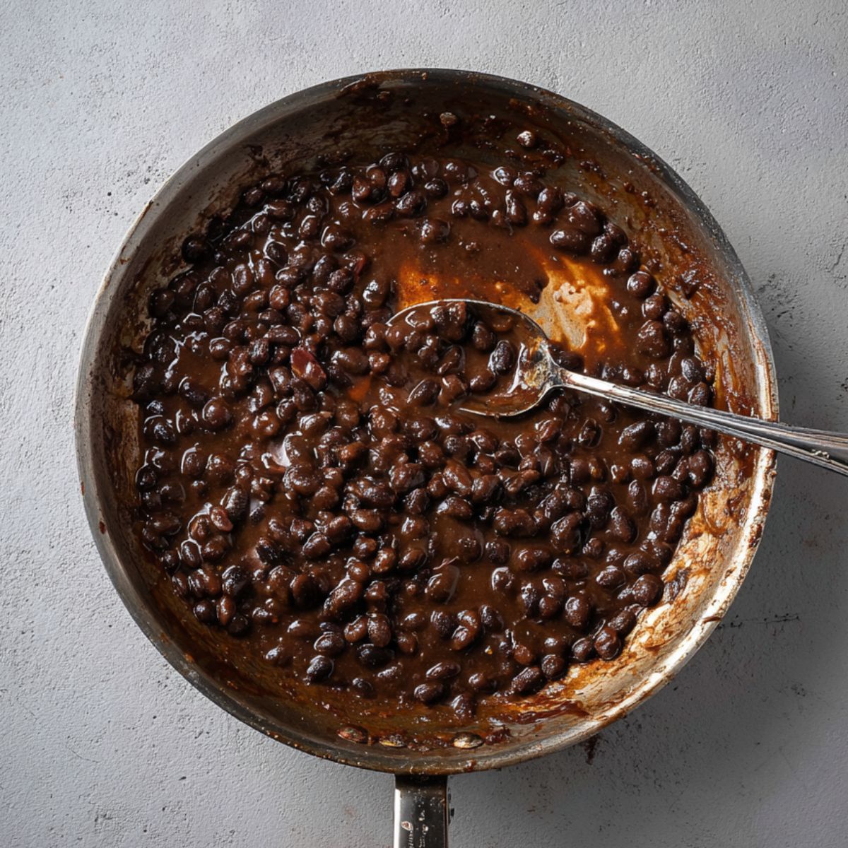 Healthy Sheet Pan Crunchwrap Recipe 10 A skillet filled with cooked black beans, coated in a rich, savory sauce. The beans have absorbed the flavors well, and the texture looks perfect for adding to a variety of dishes.