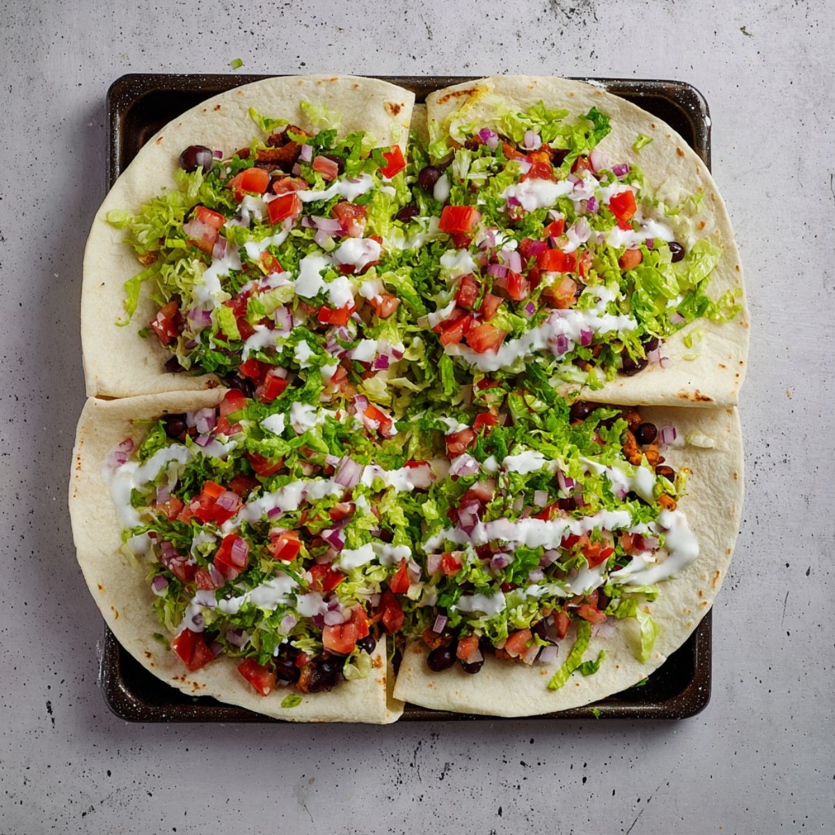 Healthy Sheet Pan Crunchwrap Recipe 11 A close-up shot of a large tortilla filled with a vibrant mix of fresh ingredients including lettuce, diced tomatoes, red onions, and sour cream. The veggies are neatly placed over the tortilla, making it look fresh and appetizing