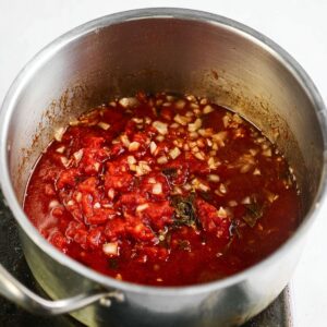 Delicious Stuffed Onions Recipe 16 A pot of tomato sauce with finely chopped onions simmering, creating a rich, deep flavor. The sauce is bubbling gently, ready to be incorporated into a recipe.