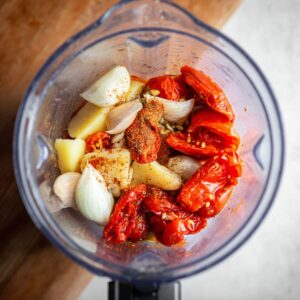 Easy Sweet Potato Cauliflower Soup Recipe 15 A blender filled with roasted tomatoes, garlic, shallots, and other vegetables, seasoned with spices and prepared for blending into a flavorful soup