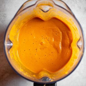 Easy Sweet Potato Cauliflower Soup Recipe 16 A smooth, vibrant orange soup in a blender, possibly a roasted vegetable blend, ready for further processing or serving