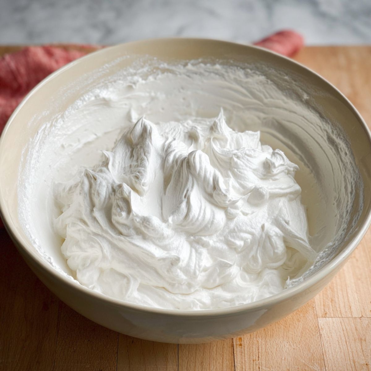 The Best Vegan Strawberry Shortcake Cake 12 A bowl of freshly whipped cream, with soft peaks, ready to be spread on the strawberry shortcake.