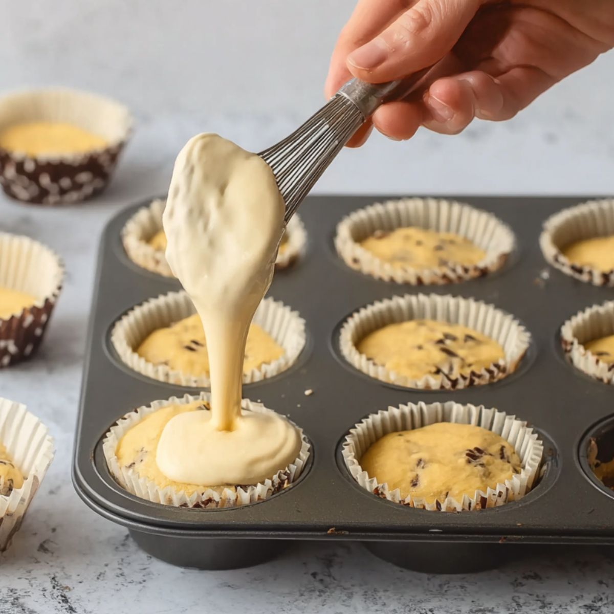 Delicious Chocolate Chunk Banana Muffins Recipe 13 A photo of the batter being spooned into muffin cups.