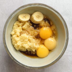 Delicious Chocolate Chunk Banana Muffins Recipe 15 A bowl with mashed bananas, eggs, and other wet ingredients, possibly before mixing.