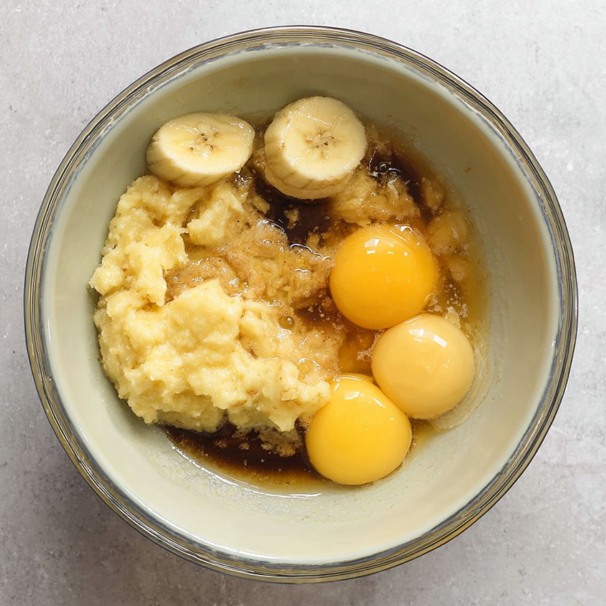 Delicious Chocolate Chunk Banana Muffins Recipe 11 A bowl with mashed bananas, eggs, and other wet ingredients, possibly before mixing.