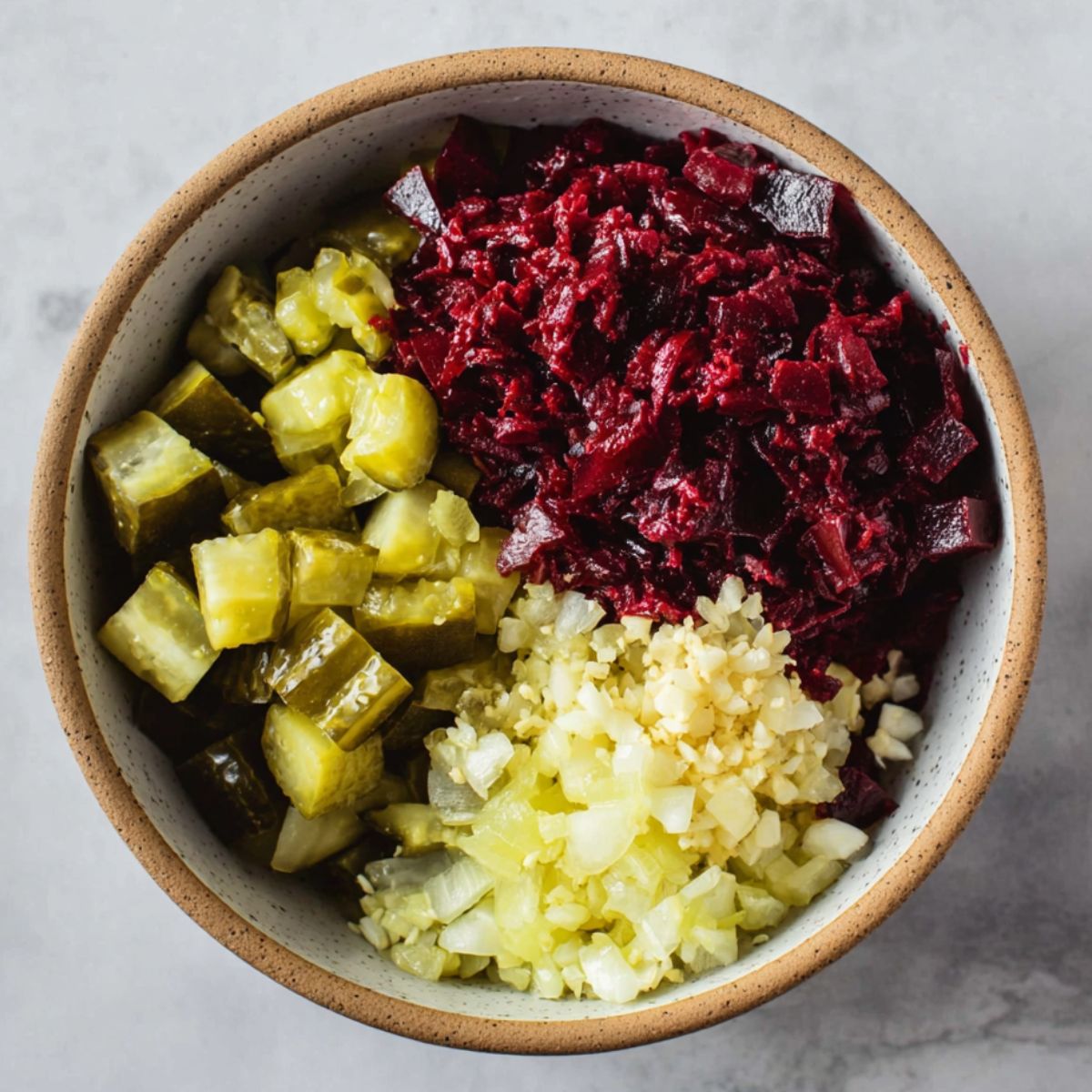 Delicious Grated Beet Salad Recipe 11 The ingredients for the salad separated in a bowl: diced pickles, grated beets, and minced garlic, ready to be mixed.