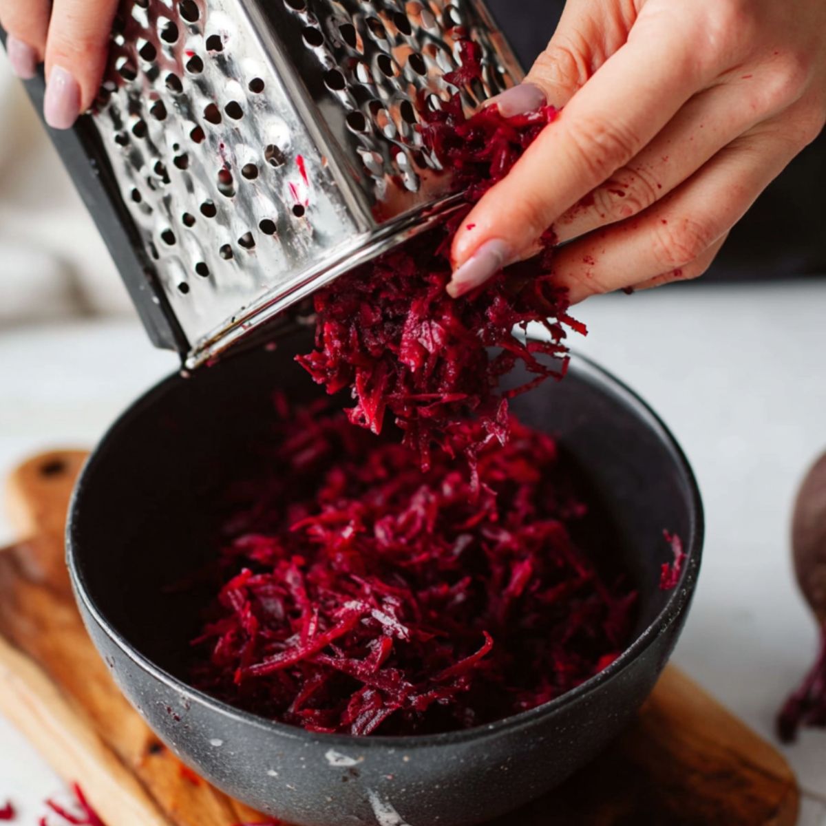 Delicious Grated Beet Salad Recipe 10 Close-up of someone grating raw beets over a bowl, showing the preparation step of shredding the beets for the salad.