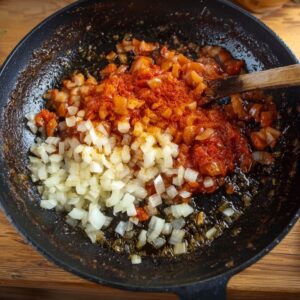 Easy Peri Peri Shrimp Recipe 15 Chopped onions and tomato paste being cooked in a skillet, starting the base of a shrimp sauce.
