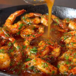Easy Peri Peri Shrimp Recipe 16 Shrimp being tossed in a skillet with fresh herbs and sauce, giving it a glossy, flavorful coating.