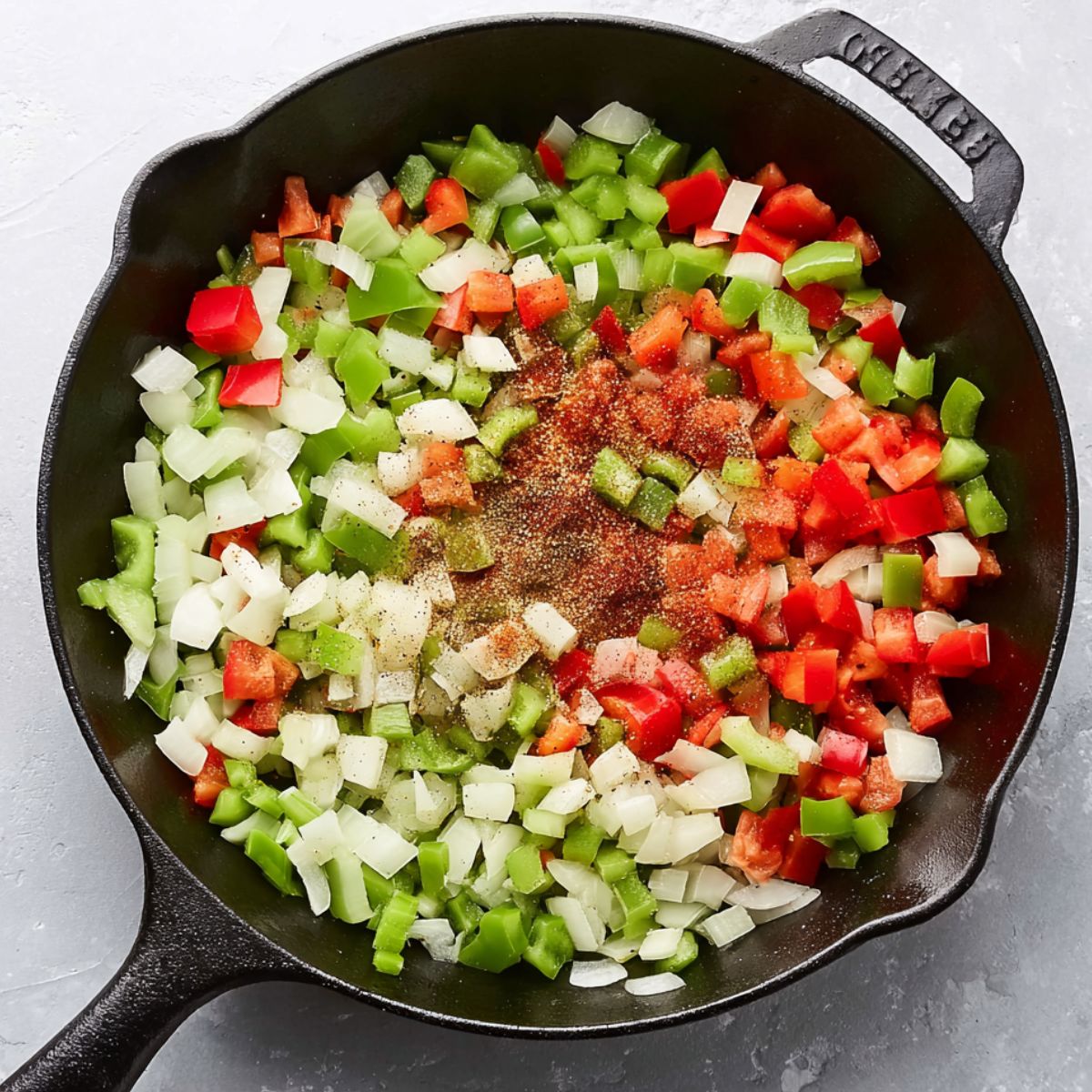 Easy Homemade Shakshuka Recipe 10 Chopped onions, red and green bell peppers, and celery with spices in a cast-iron skillet, ready to be sautéed.
