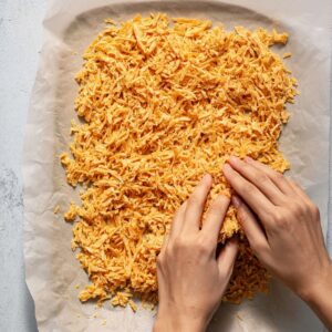 Healthy Shredded Tofu Wraps Recipe 17 A person spreading shredded buffalo tofu onto parchment paper, separating it evenly with their hands.