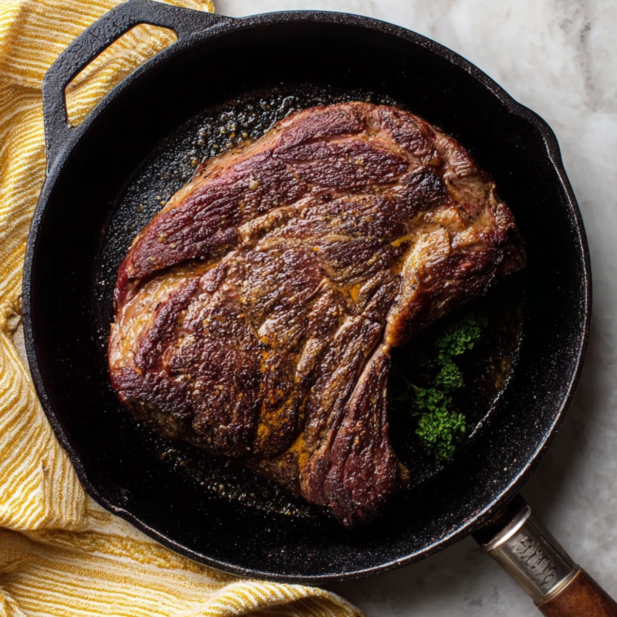 Best Mississippi Pot Roast Recipe 10 Seared beef chuck roast in a black cast-iron skillet with a yellow-striped kitchen towel on the side